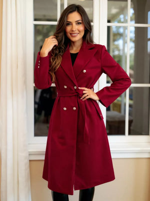 Red tailored double-breasted trench coat with waist tie and button details.