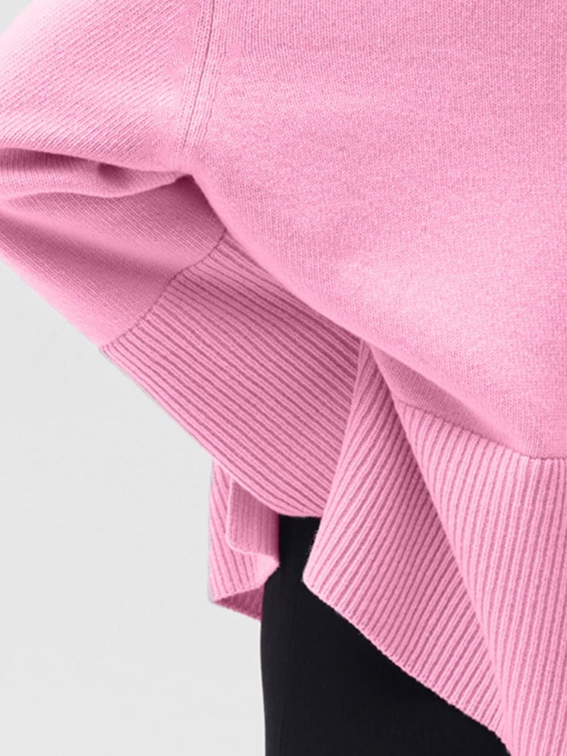 Pink ribbed knit sweater with flared sleeves and a turtleneck detail.