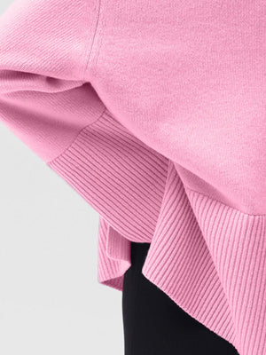 Pink ribbed knit sweater with flared sleeves and a turtleneck detail.