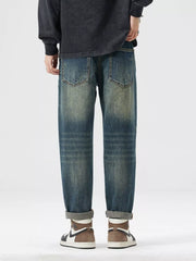 Men's distressed blue denim jeans with patchwork details and a relaxed fit.
