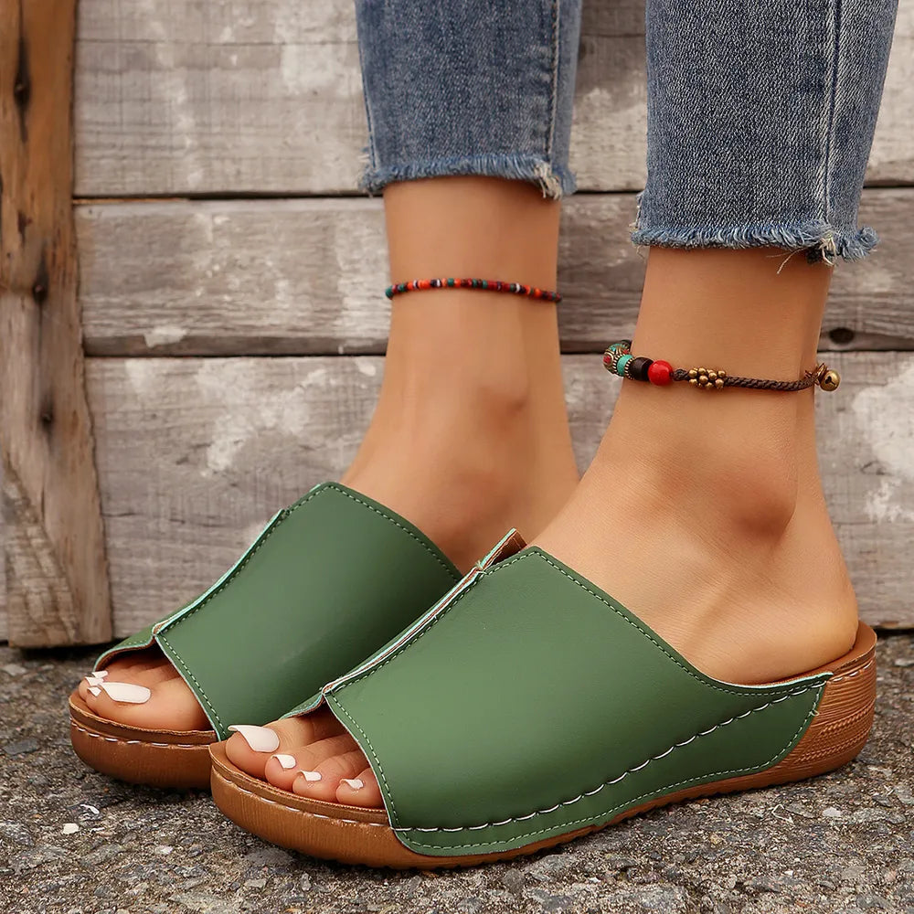 Green stitched edge wedge mules with open toe and platform sole.