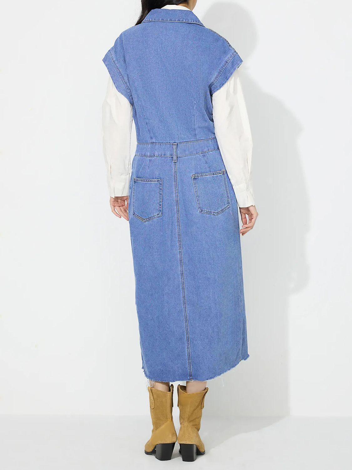Sleeveless light wash denim midi dress with buttoned front, slit, and frayed hem.