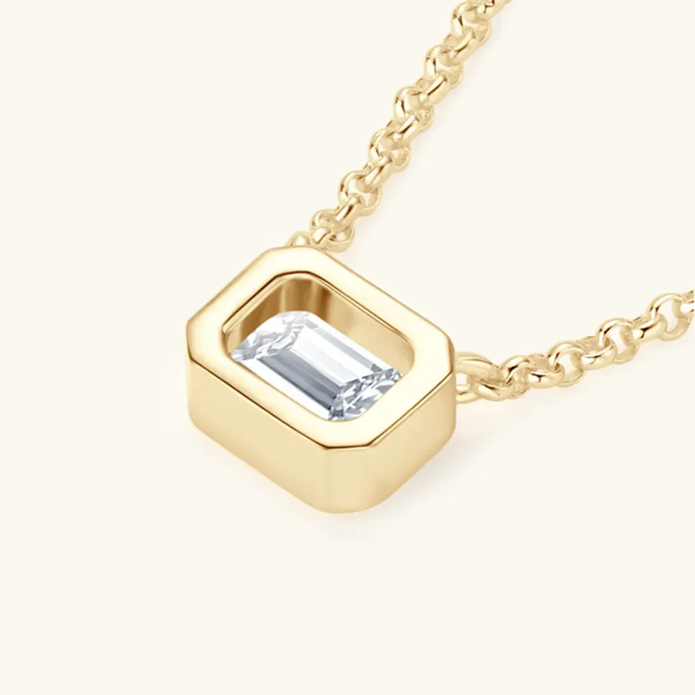 Gold necklace with emerald cut moissanite in a bezel setting.