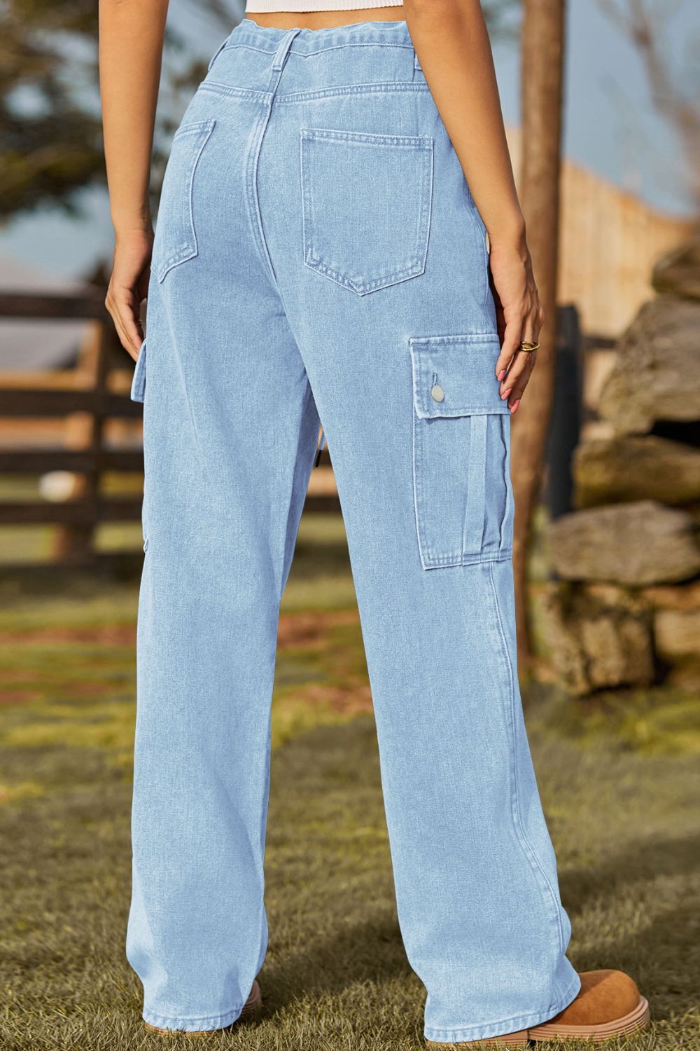 Light wash denim cargo pants with button flap pockets and wide leg.