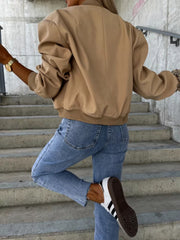 Camel faux leather bomber jacket with sculpted sleeves and ribbed cuffs, styled with jeans.