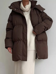 Dark brown puffer trench coat with hood and buttoned closure, worn over a cream turtleneck sweater.