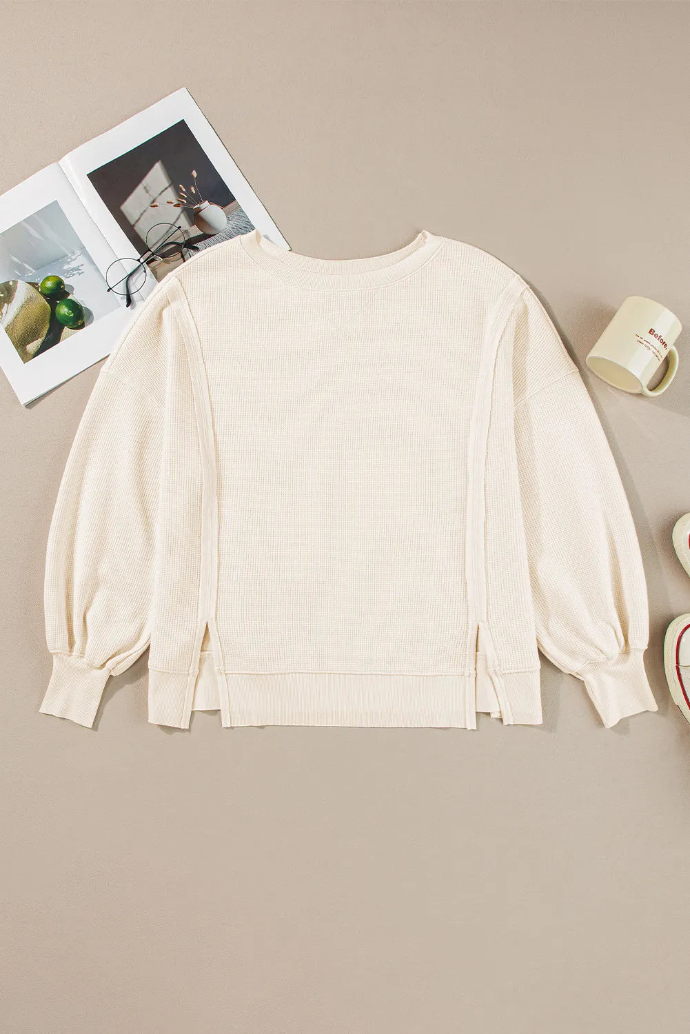 Ivory waffle knit pullover sweater with balloon sleeves and side slits.