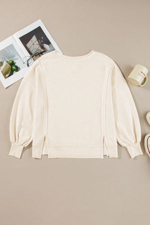 Ivory waffle knit pullover sweater with balloon sleeves and side slits.