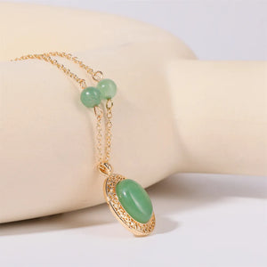 Gold chain necklace with oval neon green jade pendant and beaded accents.