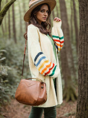 Cream knit duster cardigan with rainbow striped sleeves and a relaxed fit.