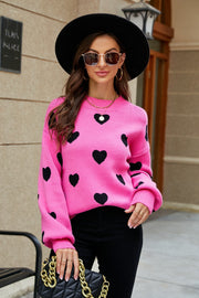 Pink sweater with black hearts, balloon sleeves, and crew neck.