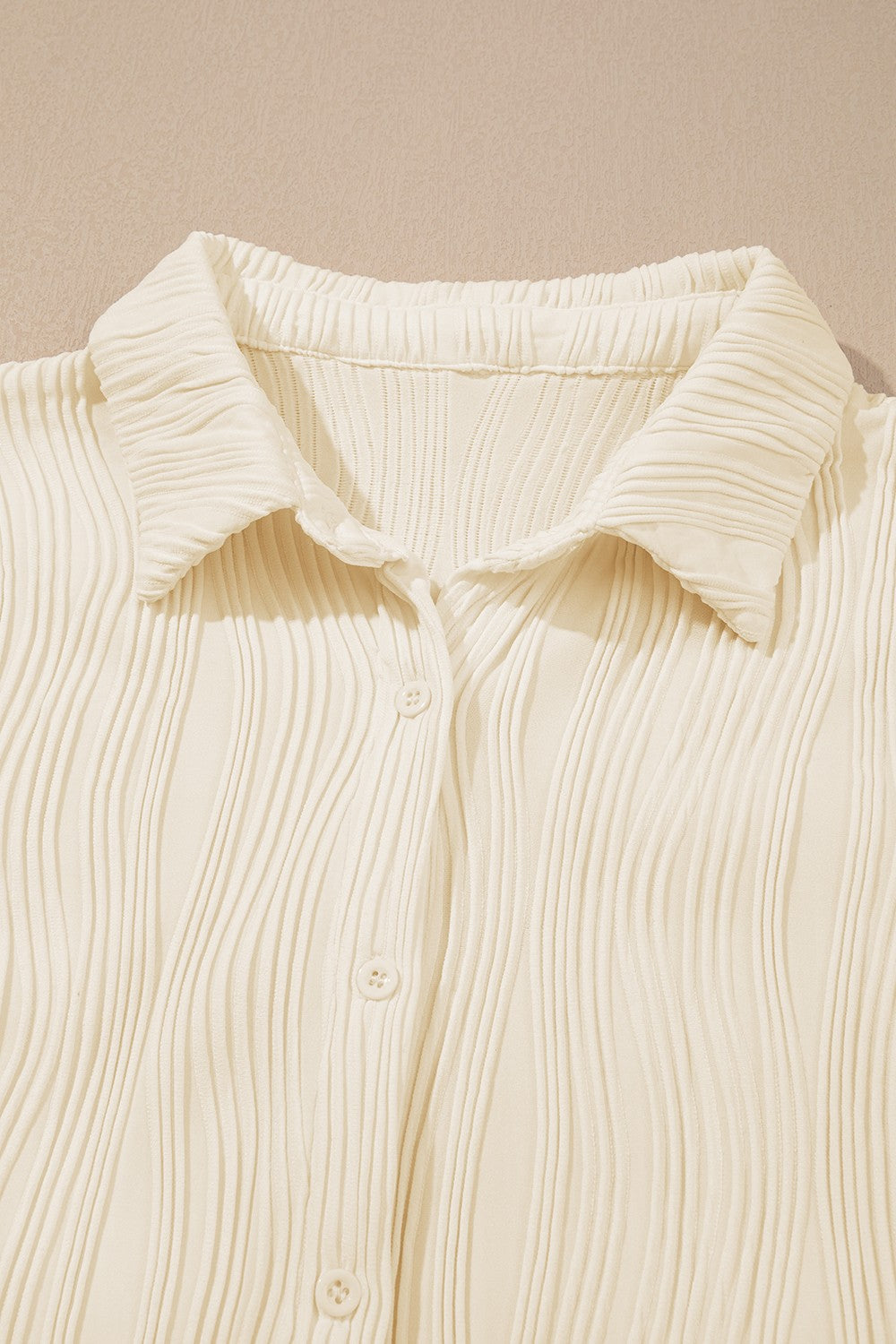 Beige pleated texture oversized button-down shirt with a classic collar and button closure.