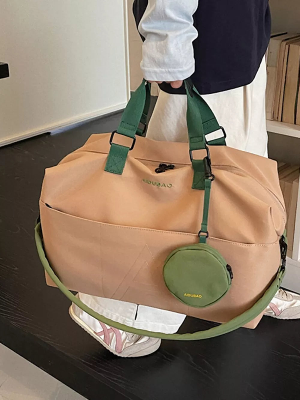 Camel nylon duffle bag with green straps and detachable pouch.