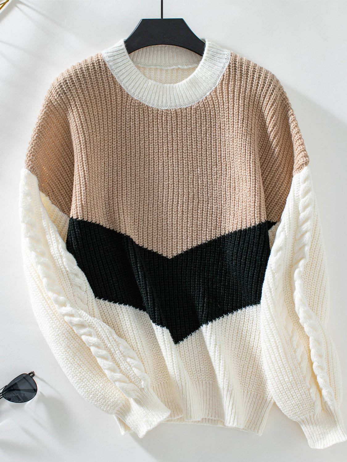 Chevron colorblock cable knit sweater in tan, black, and cream with cable knit sleeves.