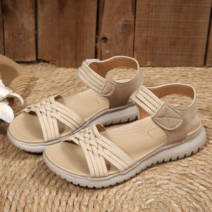 Beige woven strap open-toe flat sandals with adjustable ankle straps.