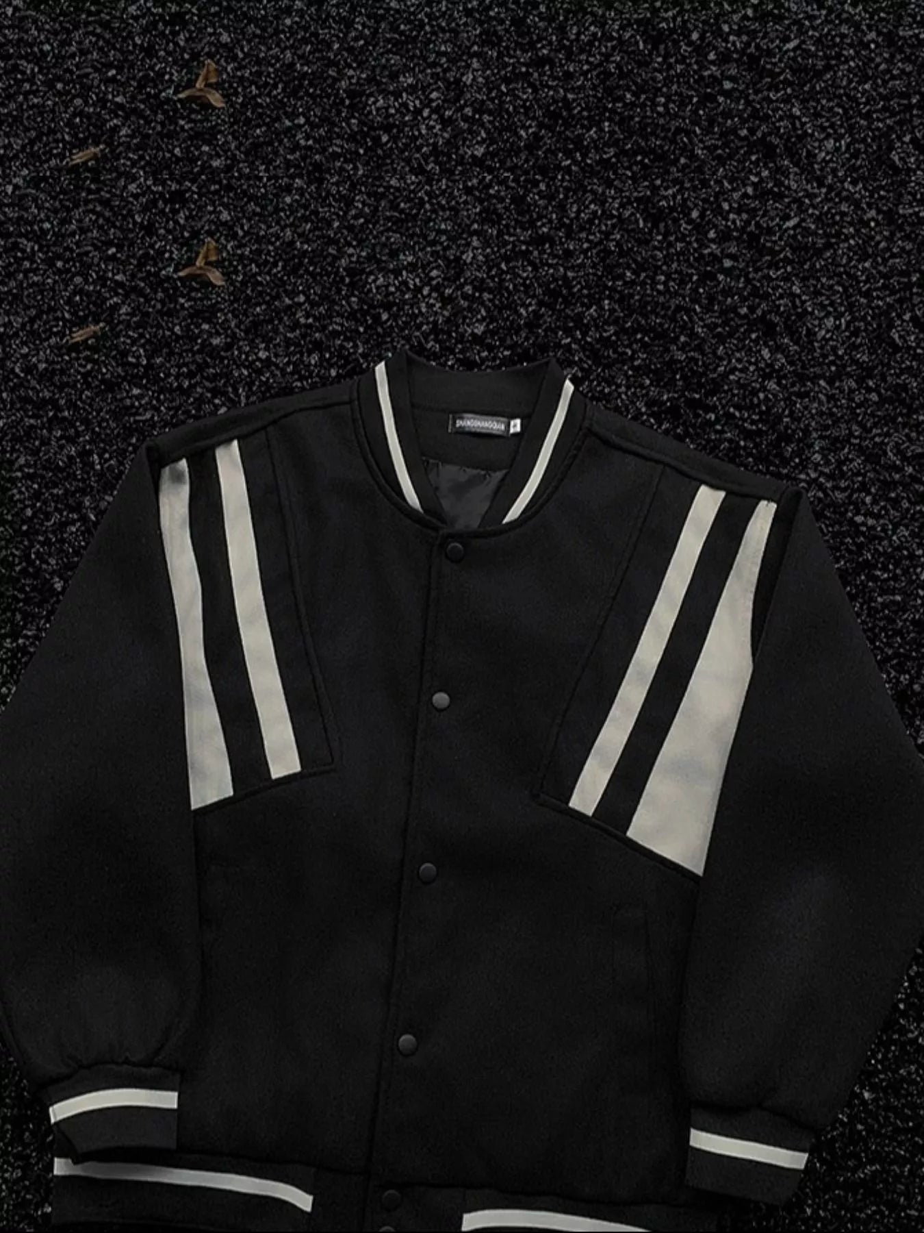 Black bomber jacket with white stripe accents on sleeves and collar, buttoned front.