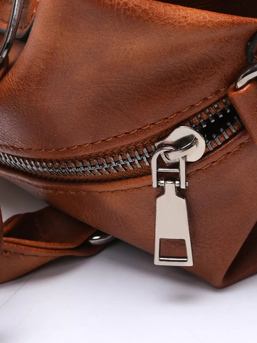 Brown leather half-moon bag with silver zipper detail and buckle.