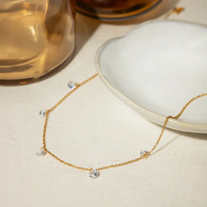 Gold dangling crystal station necklace with a delicate chain and clear stones.