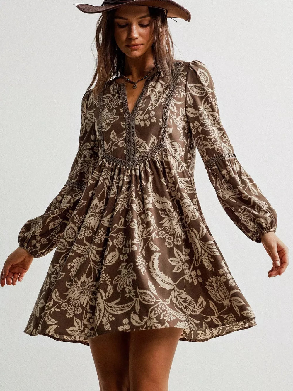 Brown floral print long sleeve mini dress with notched neckline and balloon sleeves.