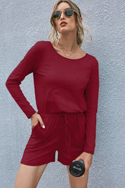 Wine jersey pocket romper with drawstring waist and long sleeves.