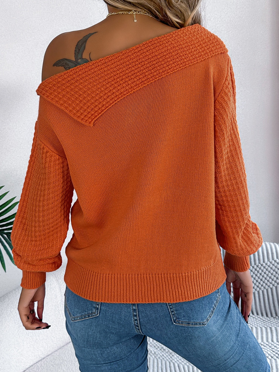 Orange off-shoulder cable knit pullover sweater with textured sleeves and neckline detail.