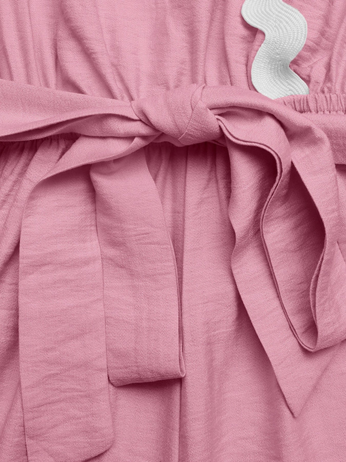Pink maternity wrap romper with tie waist and white scalloped trim detail.