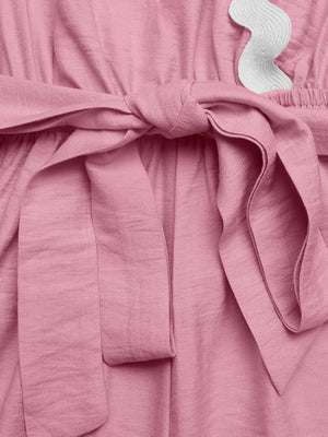 Pink maternity wrap romper with tie waist and white scalloped trim detail.