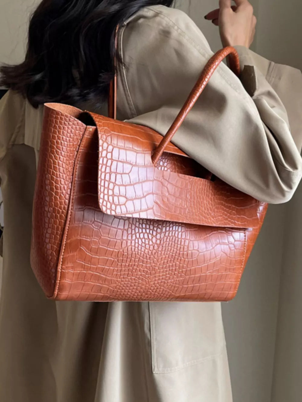 Brown crocodile-embossed medium tote bag with flap closure and top handle.