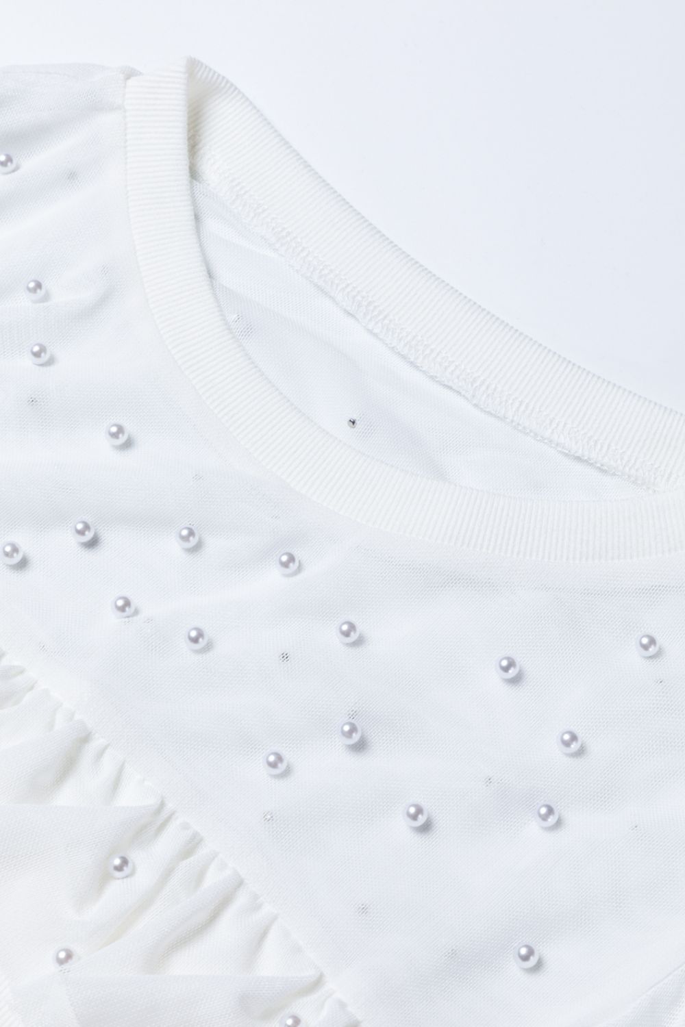 White mesh bodysuit with pearl embellishments and ruffled detail
