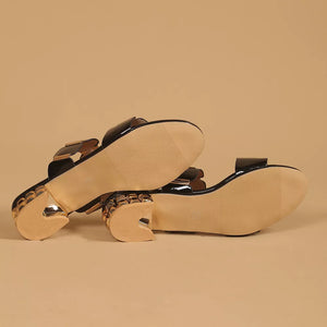 Black patent block heel sandals with gold accent details and textured heels.