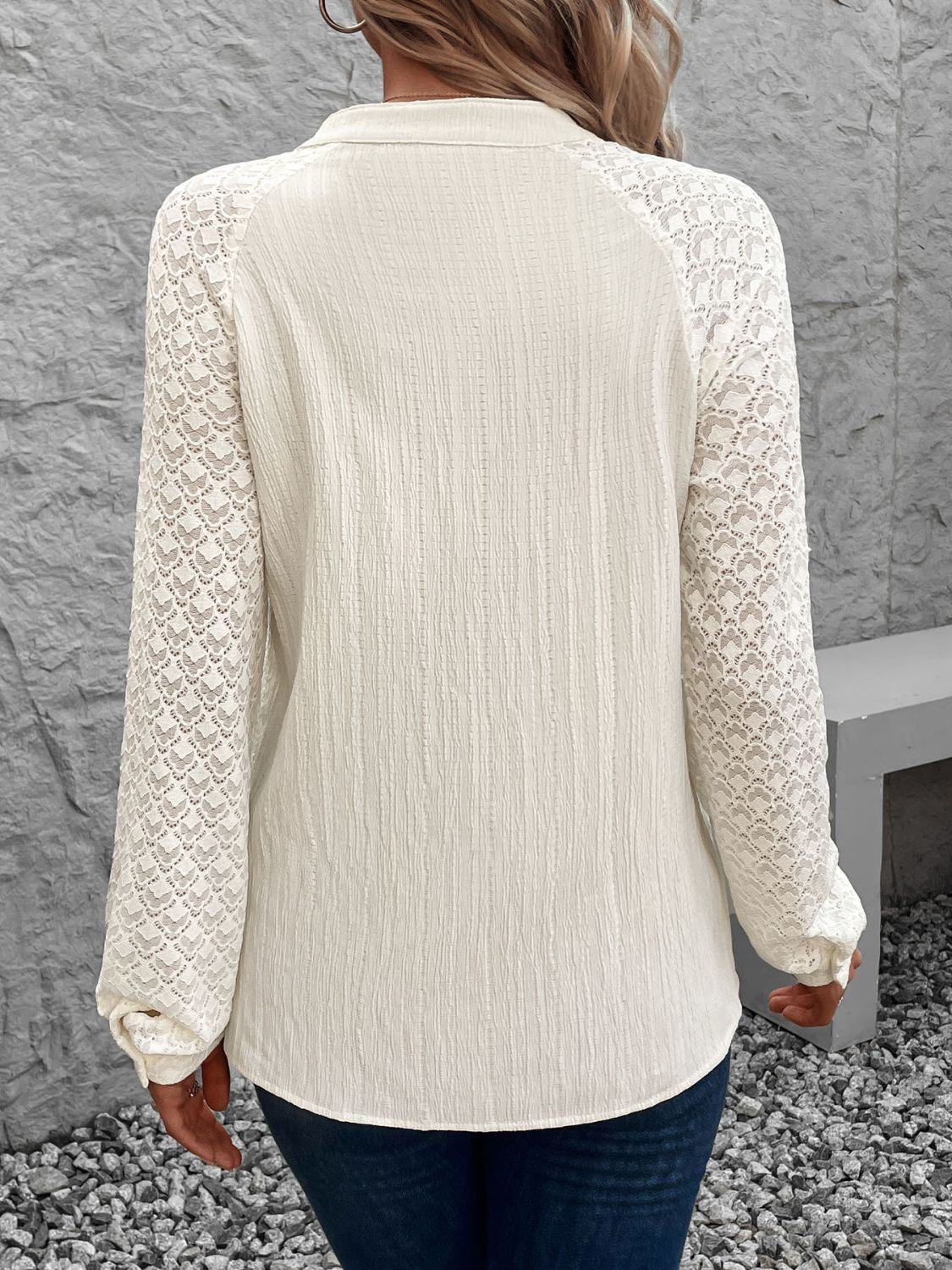 Cream lace sleeve raglan blouse with textured fabric and buttoned collar detail.