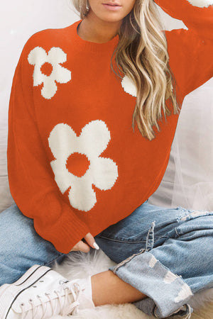 Orange acrylic crewneck sweater with white floral intarsia pattern.