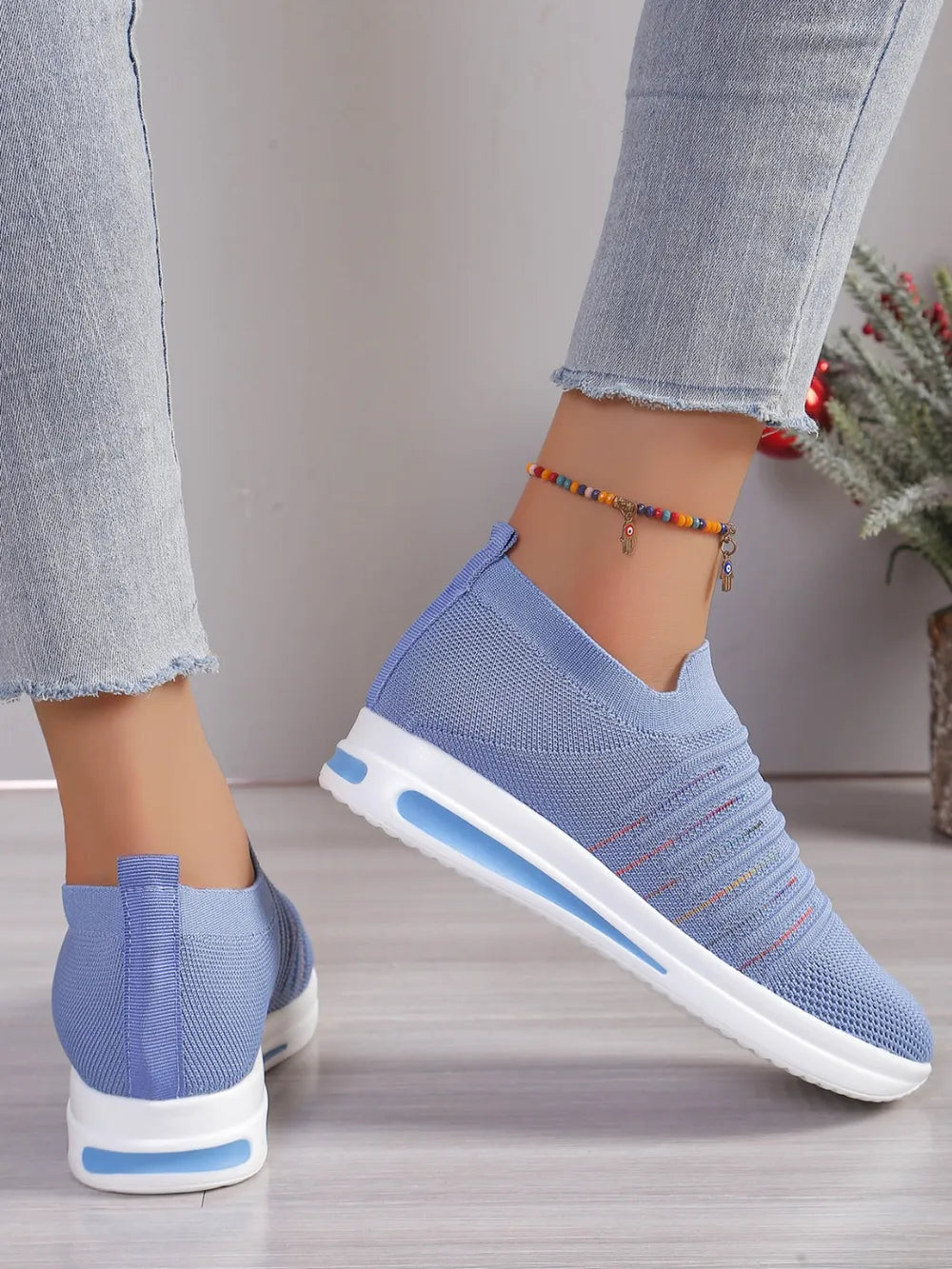 Light blue knit slip-on wedge sneakers with subtle striped detail and white soles.