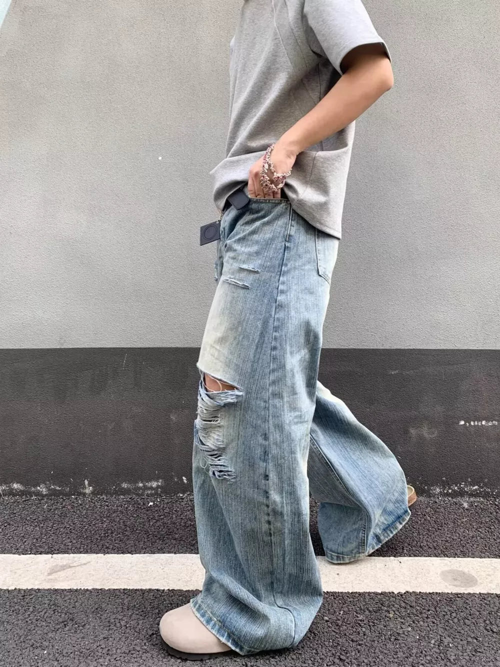Distressed wide-leg jeans in light wash denim with pocket detail and ripped knees.