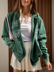 Dark green graphic zip hoodie with New York print, white t-shirt, and pleated skirt.