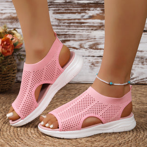 Pink mesh open-toe sandals with a chunky white sole and cut-out details.