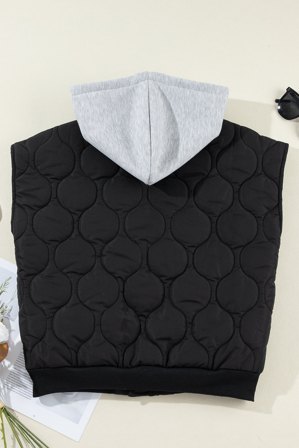 Black quilted sleeveless jacket with grey hood and ribbed hem