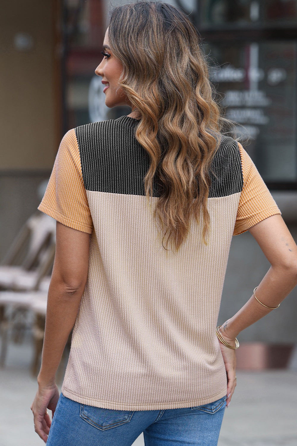 Panelled ribbed tee with textured sleeves in beige, black, and orange.