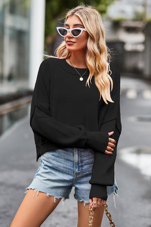 Black ribbed knit batwing sweater with crew neck and cropped length.