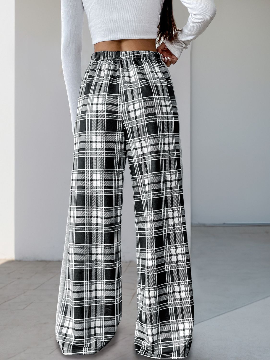 Black plaid wide-leg track pants with elastic waist and side stripe detail.