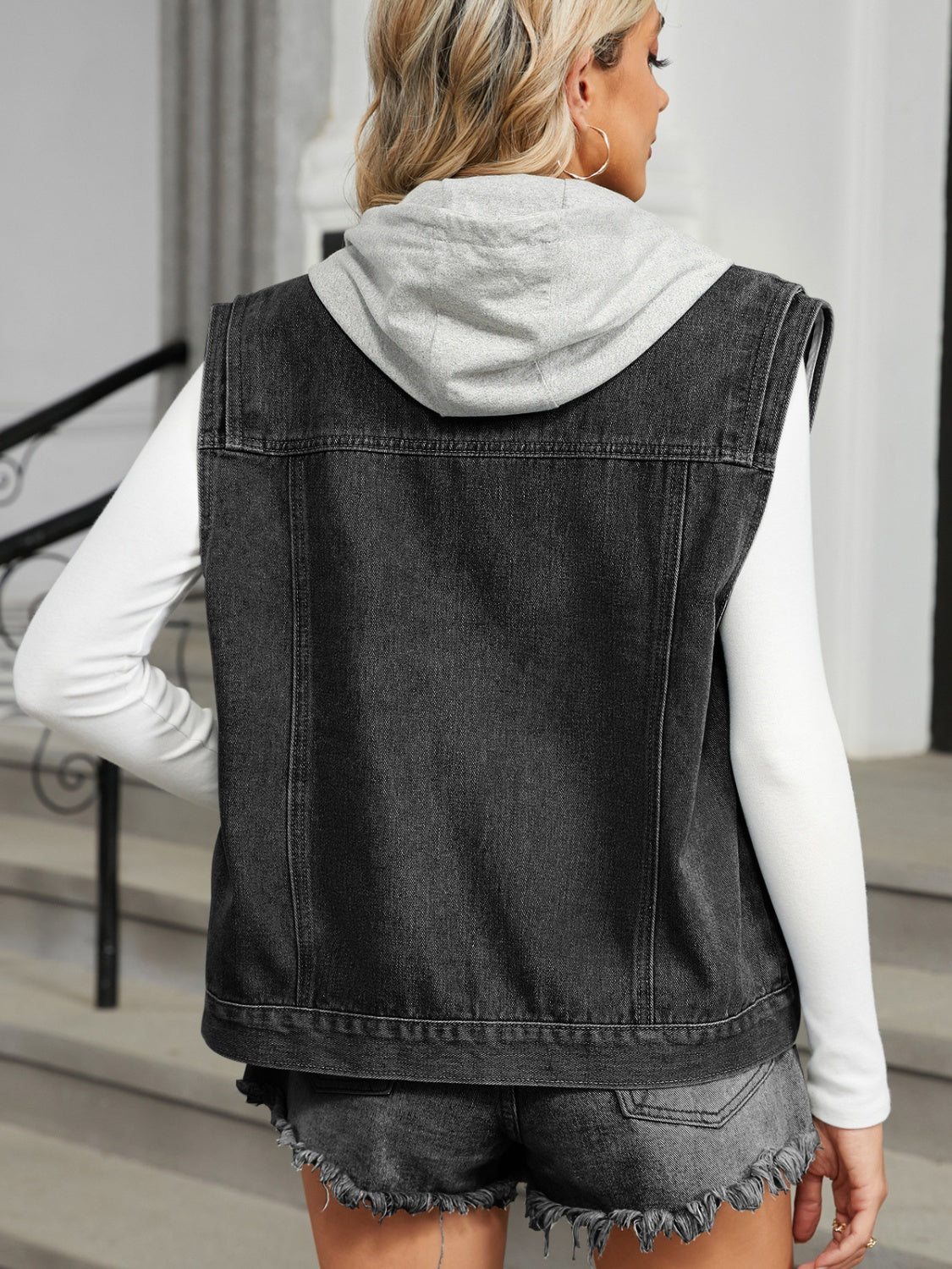 Black denim vest with attached grey hooded back detail, sleeveless, casual style.