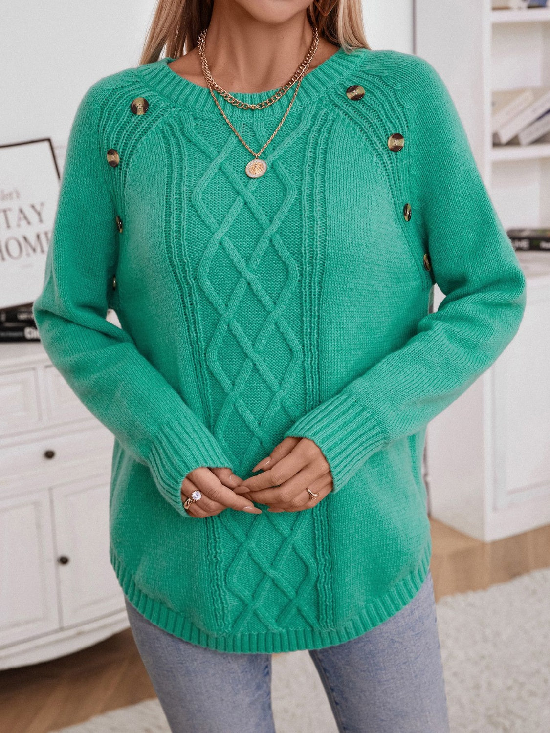 Green cable knit raglan sweater with button shoulder detail and crew neck.