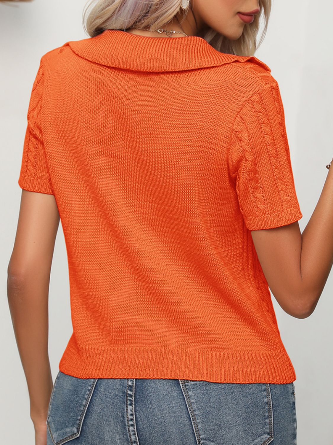 Orange knit short sleeve polo sweater with cable knit sleeves and collar.