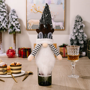 Festive gnome bottle topper in dark gray with sequin hat, reindeer antlers, and striped sleeves.