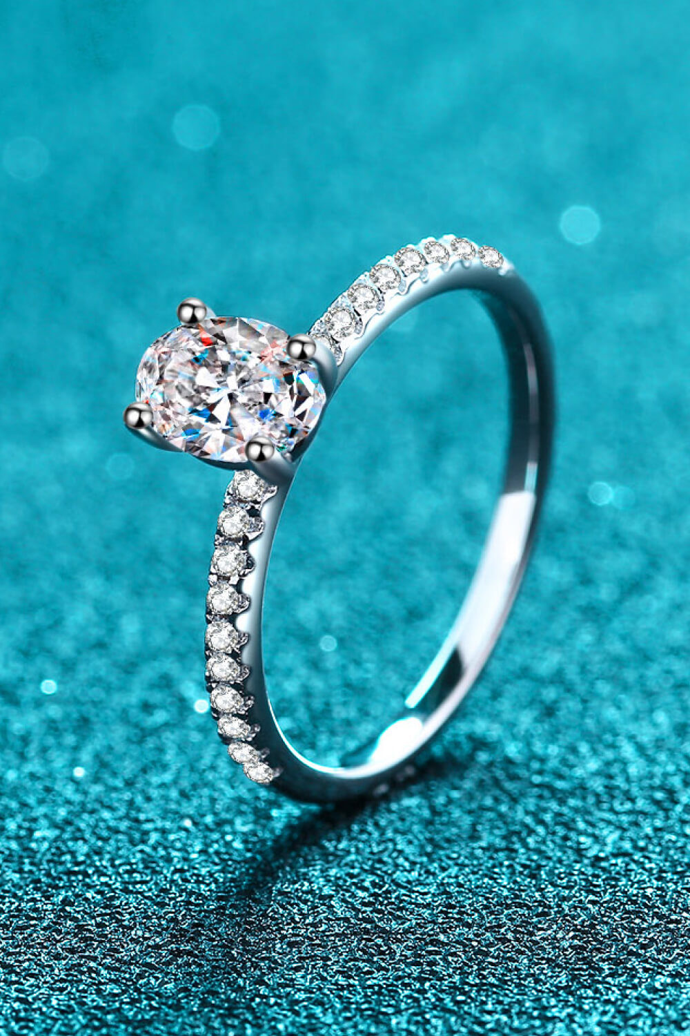 Silver moissanite ring with pavé band and oval center stone.