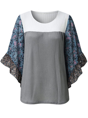 Textured panel blouse with white, gray, and blue floral flutter sleeves.