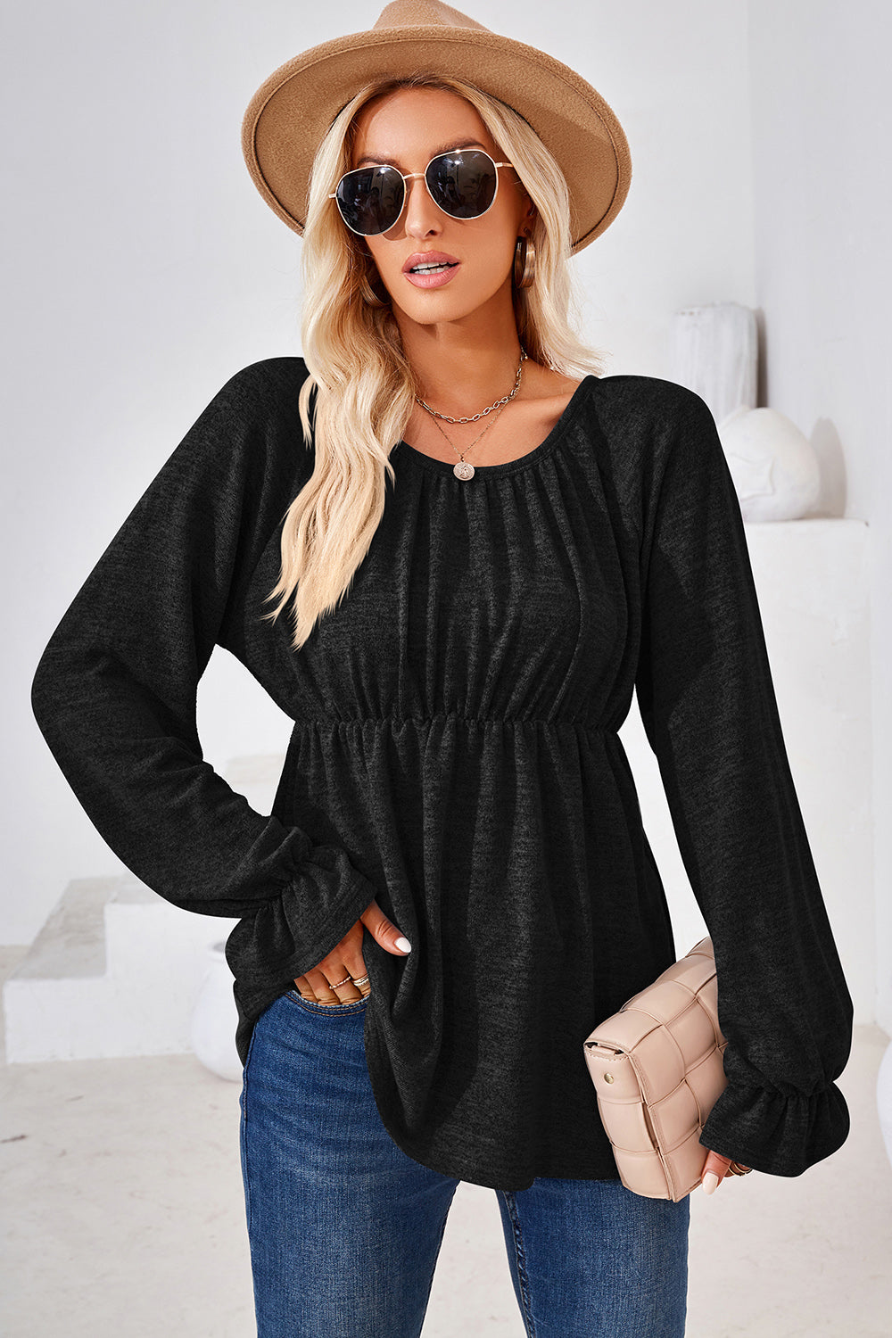 Black peasant blouse with gathered neckline and elastic waist, long sleeves with ruffled cuffs.