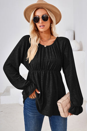 Black peasant blouse with gathered neckline and elastic waist, long sleeves with ruffled cuffs.