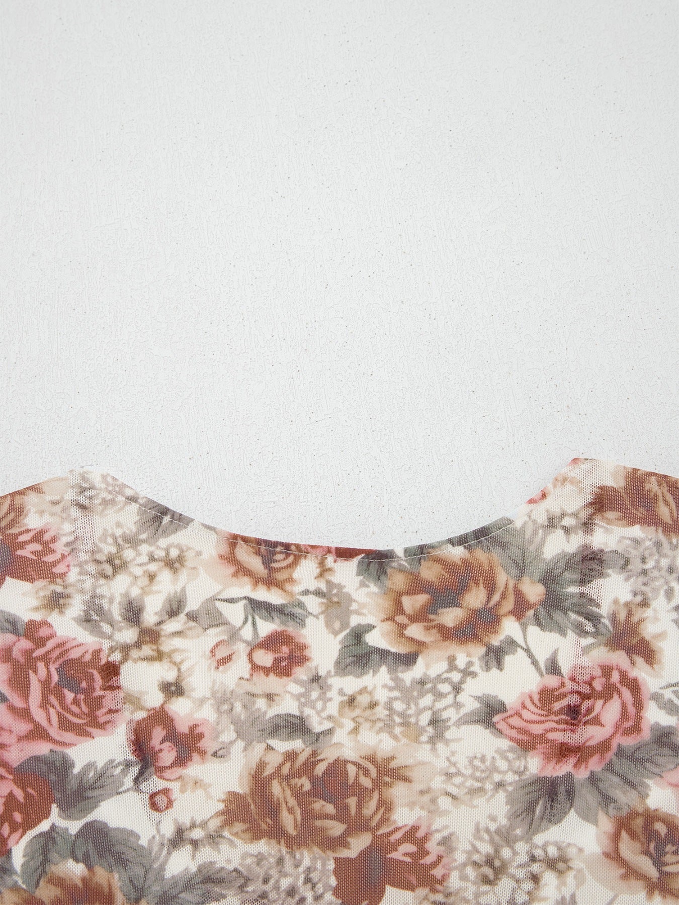 Charming floral mesh blouse with a round neckline and ruffled detail.