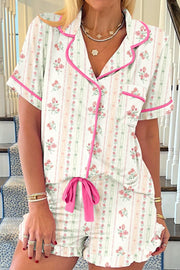 Pajama set with floral print, pink trim, button front, short sleeves, and ruffled shorts.